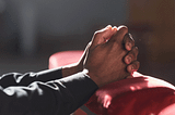 Clasped hands of man praying in church.