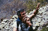 boy standing in front of a man in a rocky terrain during daytime