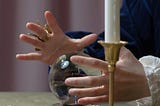 A person waving their hands around a crystal ball like a fortune teller