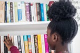 Young black girl chooses book from shelf