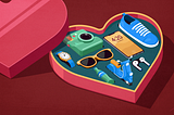 Heart-shaped box with various objects inside, including a camera, watch, sunglasses, smartphone, shoe, soda bottle, vespa and wireless headphones.