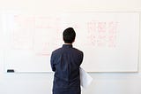 Man looking to a whiteboard full of mobile app wireframes