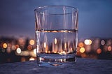 A cup of water with a city view on the background