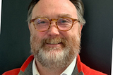 A balding middle-aged man with glasses and a beard.