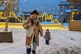 Me in a hat and jacket made from an old french curtain standing in the snow; my daughter Ophelia is in the background