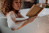 Woman relaxing in tub while reading a book