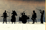 Silhouettes of jazz musicians in front of brick wall.
