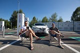 Electric car charging while we are sitting on lawn chairs reading a book in front of it.