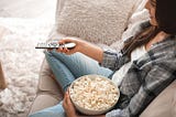 Woman on the couch with popcorn watching a movie