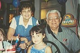 The author as a young girl, with her grandparents behind her, posing for a photo at her birthday party.