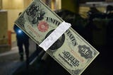 Taped 1917 dollar bill over blurred photo of night watchman.