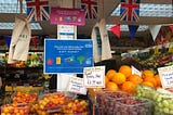 A fruit and veg stall at Bury Market with a sign saying “shop with your NHS Healthy Start card at your award-winning Bury Market”