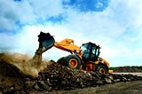 A cover image: an excavator on a pile of garbage.