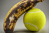 Brown banana leaning on a tennis ball