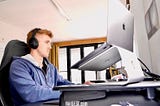 man wearing headphones and sitting at a computer desk