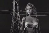 Allison Hayes in Attack of the 50 Foot Woman (1958) in a scene in which, wearing a bustier in the dark, she appears taller than an electricity pylon.