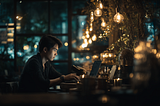 Image of a man working at night in a dimly lit cafe.
