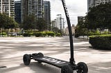 A closer look at a parked Yawboard electric skateboard/scooter in a city setting.