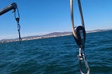 Blocks and tackle hang from davits on a sailboat’s stern