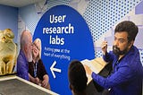 Mural outside the user research lab with 4 people around the words ‘user research labs. Putting you at the heart of everything’