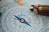 A partially colored in picture of a compass in a coloring book.
