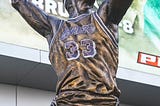 Bronze statue of Kareem Abdul-Jabbar wearing his Lakers jersey taking a shot