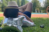 guy laying on grass, lookin at a swimming pool, with a bag-in-box as a pillow