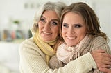 An older mother holding onto her adult daughter.