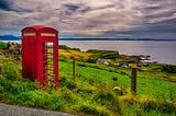 A lonely iconic red phone booth overlooking the water on the Isle of Skye
