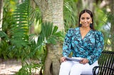 Tamika Bickham sits on bench in outdoor park with iPad in hand.