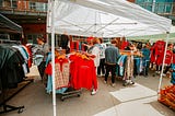 People shop at a pop-up market with secondhand Husker shirts outside in the Railyard