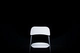 Image of a white folding chair on a black backround