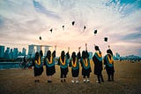 Image of college graduates throwing their graduation caps in the air