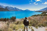 traveller standing at the edge of a cliff looking out to Glenorchy on the road out of Queenstown New Zealan