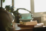 Coffee mug balanced on book and journal. Image courtesy of Samson Katt @ Pexels