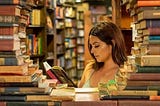A woman reading a book surrounded by books