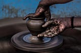 Hands creating a pot on the pottery wheel