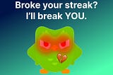 A blue and green gradient background with the Duolingo green owl mascot looking angry with its eyes glowing read and a broken heart emoji below the text “Broke your streak? I’ll break you.”