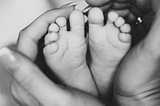 Hands holding a new born baby’s feet. Courtesy of ©2024 TROOLSocial