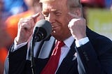 Donald Trump maniacally points both his index fingers at his own head.