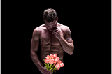 topless man holding roses against a black background; alt-text for “I am the Guy in the Contemporary Romance Novel & I’ll wait for you”