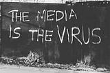 Walled graffiti that states “The media is the virus”