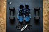 A photo with a pair of shoes, skipping rope and a pair of dumbbells to show a person working out