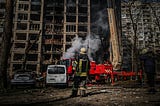 A fireman standing in front of a burnt building