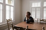 Man holding head in hands seated at table