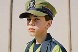 A boy wearing a mix of tradesman and military clothes.