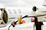 Luxury. Fabulous female pulled up in a fancy car next to her private jet ready to take on the day.