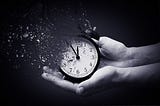 Two hands holding a dissolving small clock