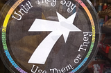 Circular sign on a cafe door, around the edges are rainbow colors and the text “Until they say, use them or they”