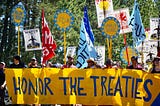 People stand behind a banner reading “Honor the Treaties” at a protest against Line 3.